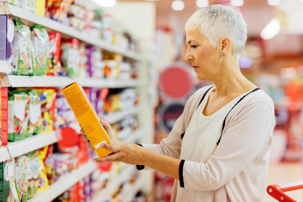 Mulher 40+ aprendendo como ler rótulos de alimentos no supermercado